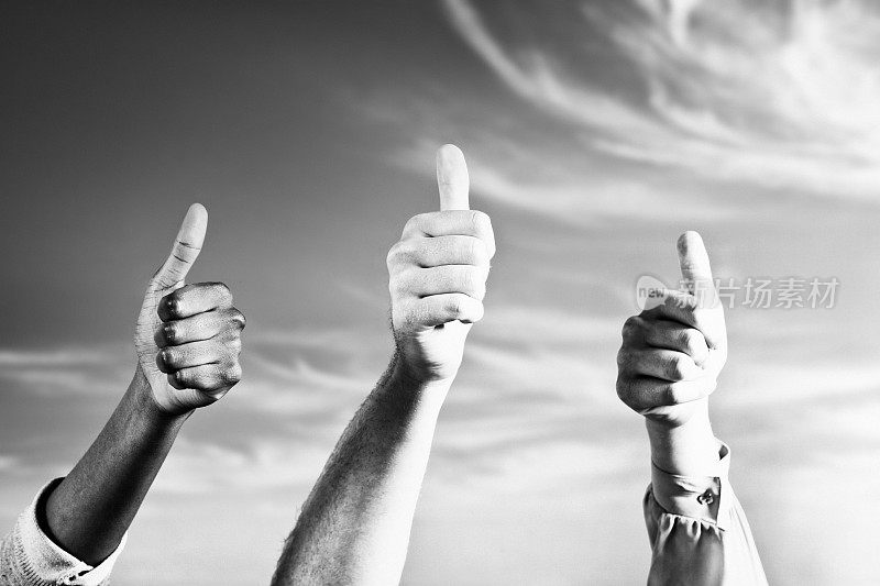 Hands making thumbs-up gesture, held aloft against a summer sky with a dusting of cloud